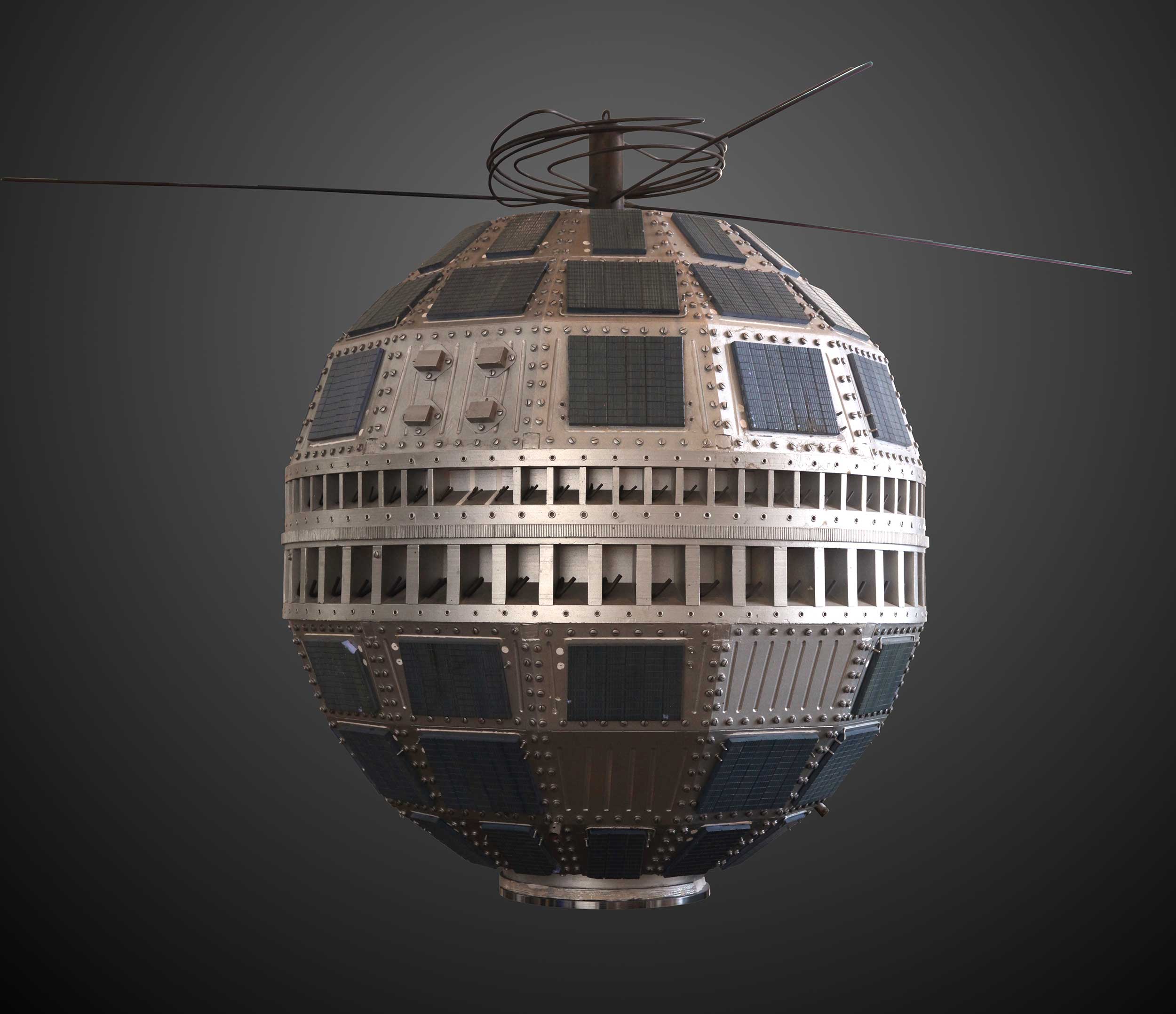 An angular globe-like satellite with panels and wires, floating on a dark grey background