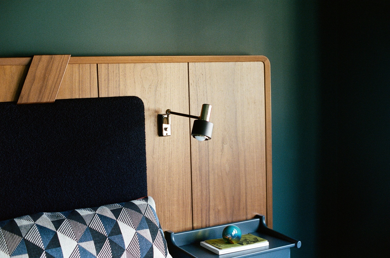 In the primary suite, a custom walnut headboard upholstered in ultramarine boiled wool by Rose Uniacke embowers Stilnovo sconces and vintage nightstands.