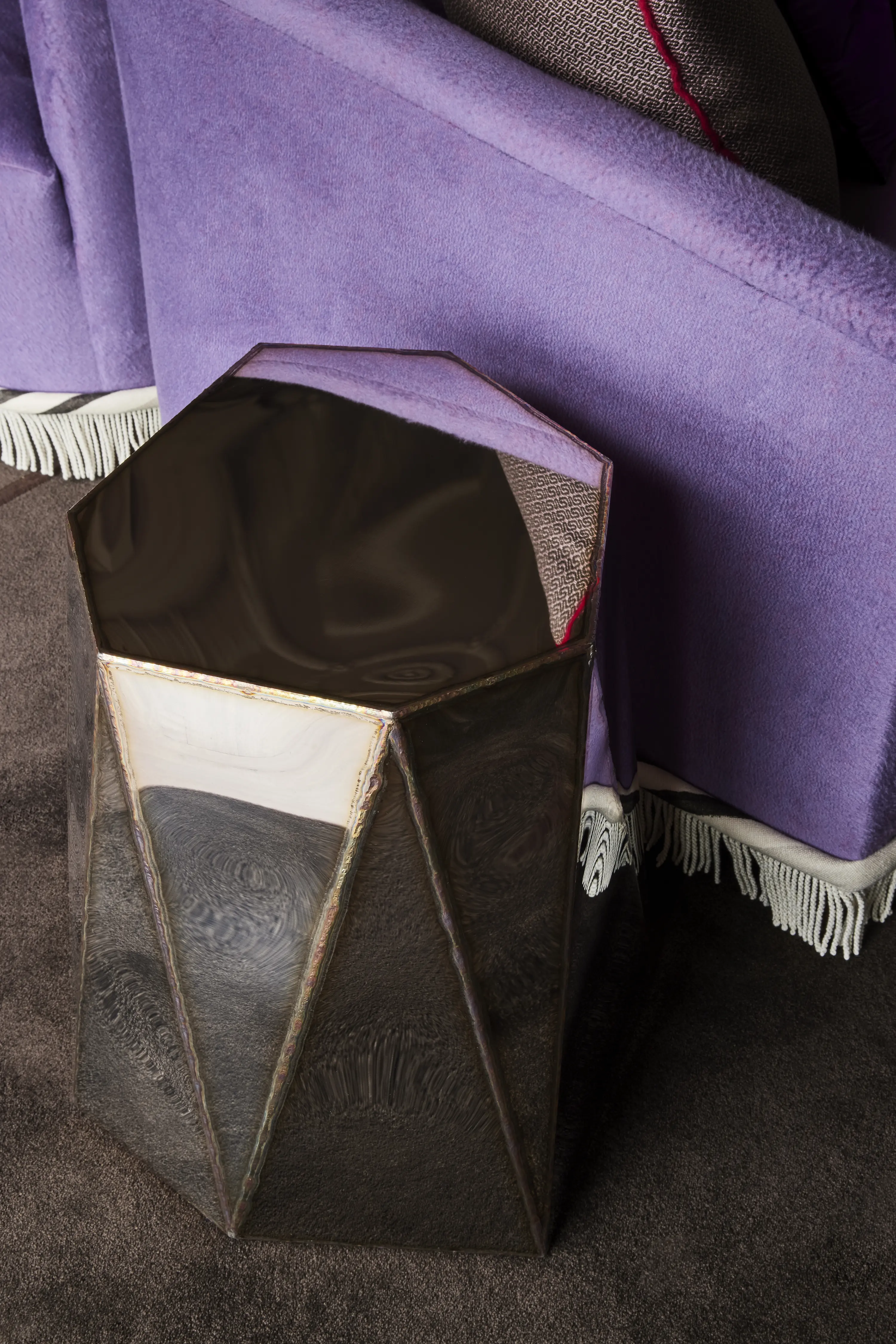 Julian Mayor's mirror-finish stainless steel side table at the arm of a custom Chroma double-sided sofa upholstered in Sandra Jordan Prima Alpaca.