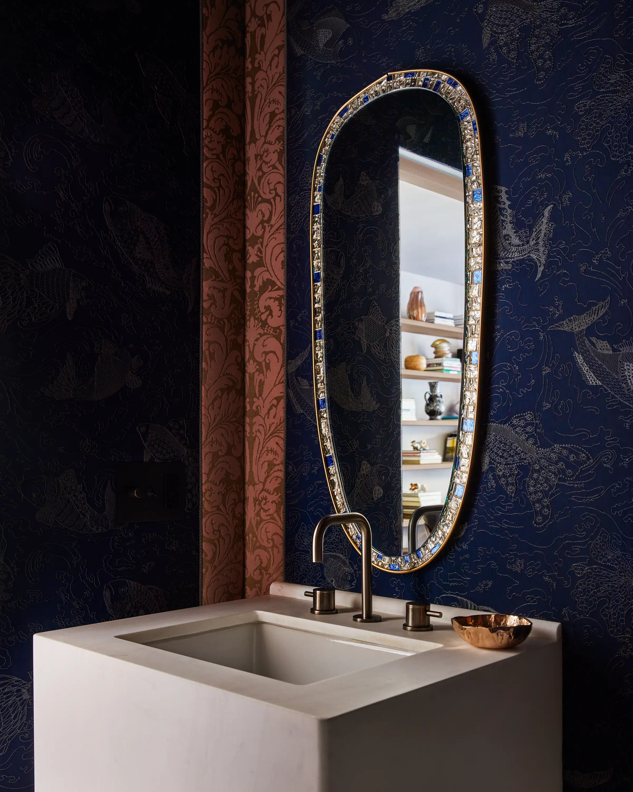 A vintage mirror of mysterious provenance is delicately adorned by a Small Furrowed Bowl by Nancy Pearce in the powder room, draped in a custom-dyed Pierre Frey wallcovering and Fortuny wallcovering with de Le Cuona trim.