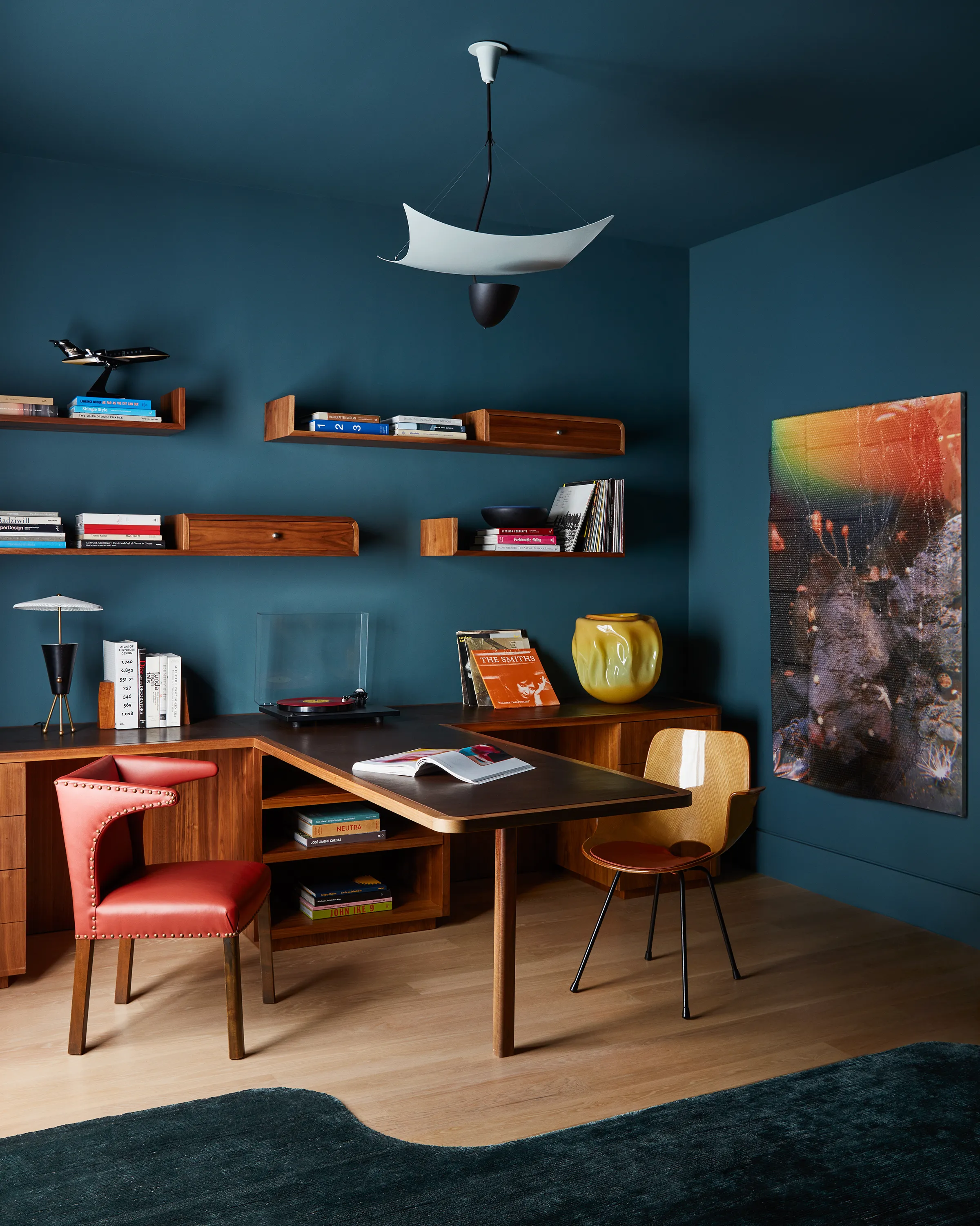 A vintage Model 12385 Vela Ceiling Light by Angelo Lelli suspends above a Medea Armchair by Vittorio Nobili and vintage Frits Henningsen lounge chair in league with a custom Chroma desk tipped in Ashbury leather and Hugh Scott-Douglas’s “Natural History.”
