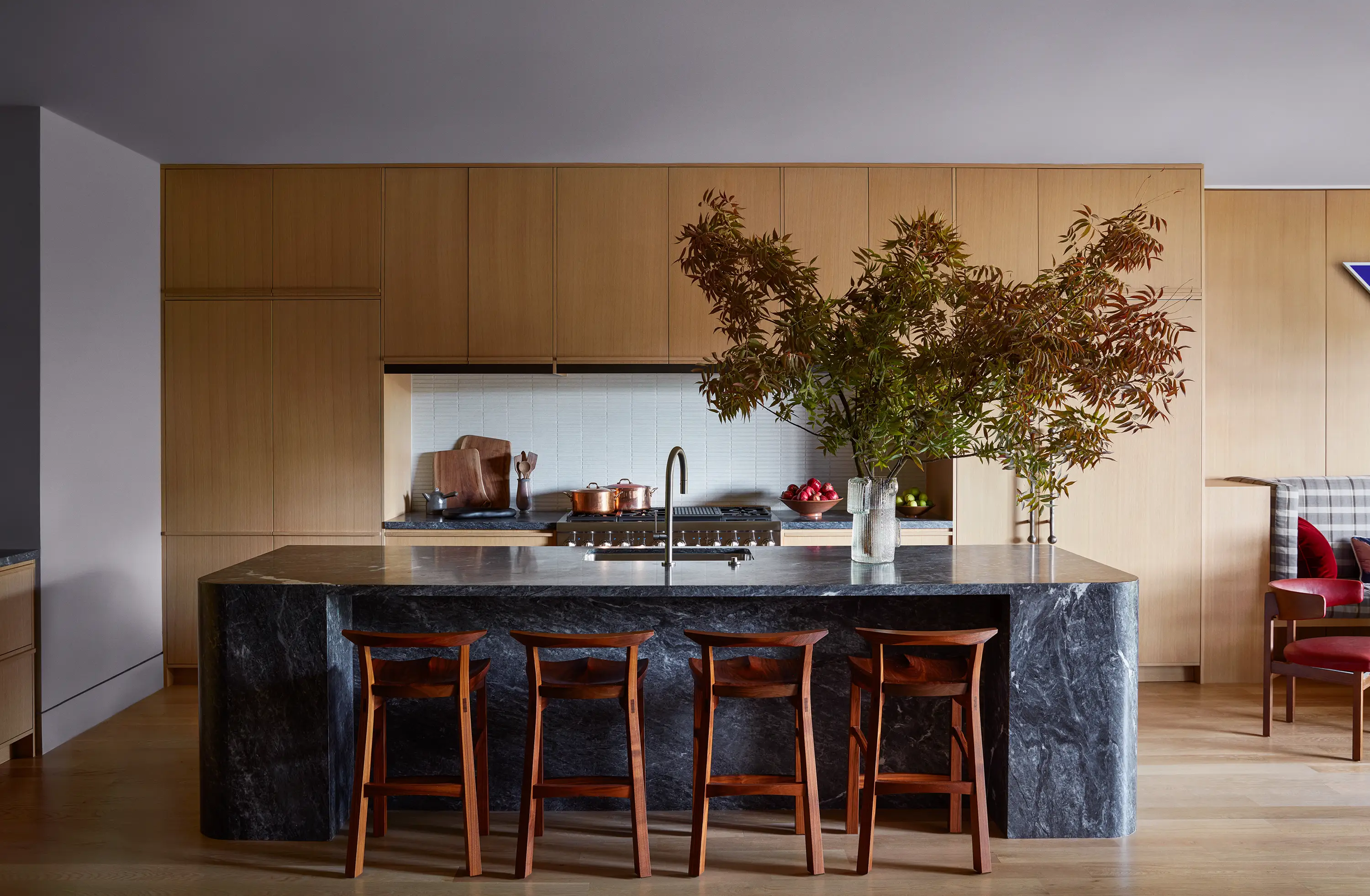 Sunny oak cabinetry and porcelain complement the elegant gray grain of a custom Bardiglio marble island arrayed with Edo Stools in walnut by Thos. Moser.