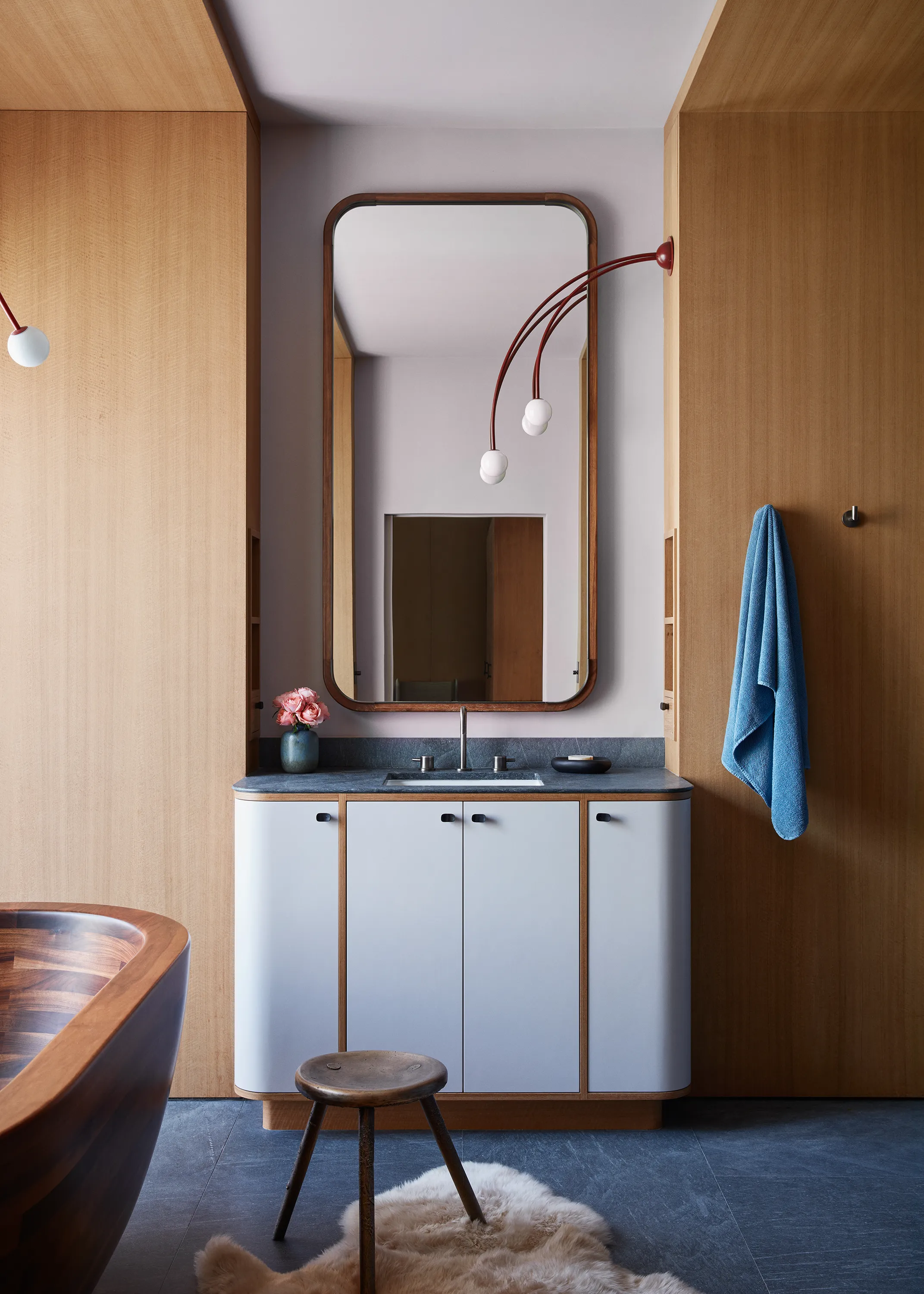 In the primary bath, a Fontana Amorosa Jet Deux Light by Michael Anastassiades modishly cascades above a custom Chroma mirror and cabinet with walnut trim.