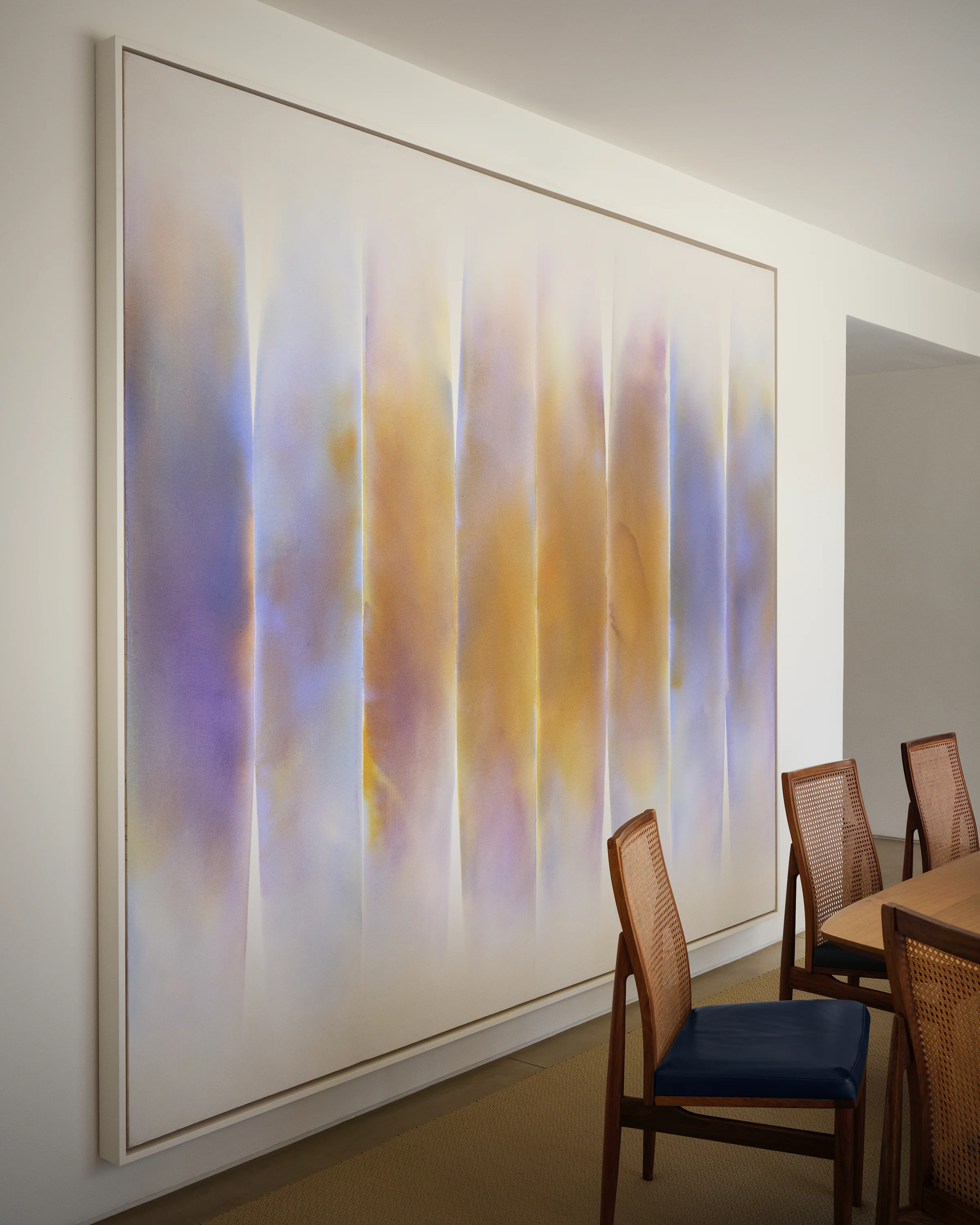 Large-scale abstract painting in lavender and gold tones presides over vintage cane dining chairs with navy leather cushions in contemporary Sonoma dining room designed by Chroma.