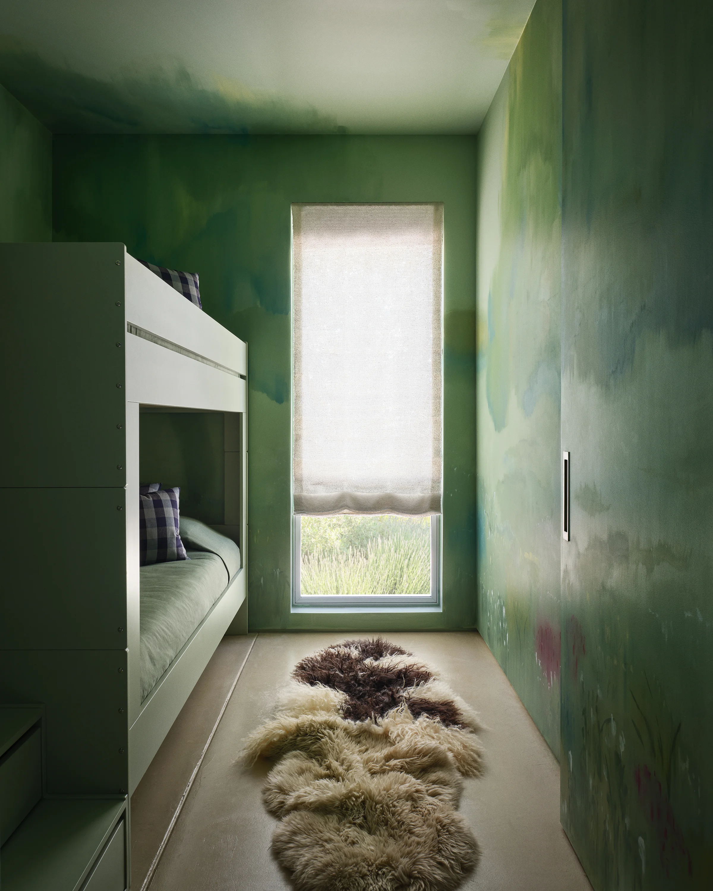 Custom green bunk beds nestle into atmospheric sage green mural walls with sheepskin rugs and garden views in serene Sonoma kids' bedroom by Chroma.