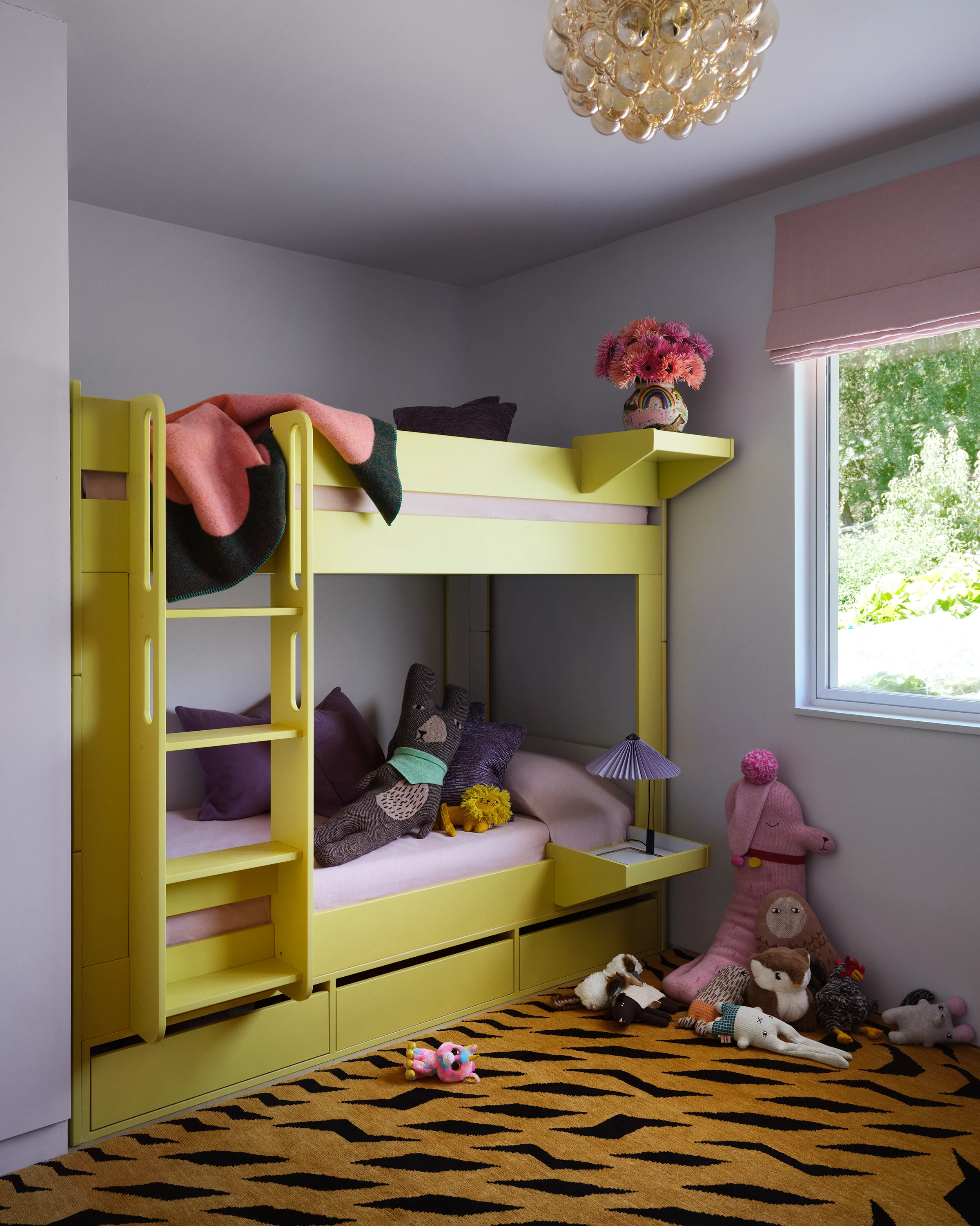 Custom chartreuse bunk beds with built-in storage display coral dahlias beneath vintage chandelier with bold tiger print rug in playful Sonoma children's room.
