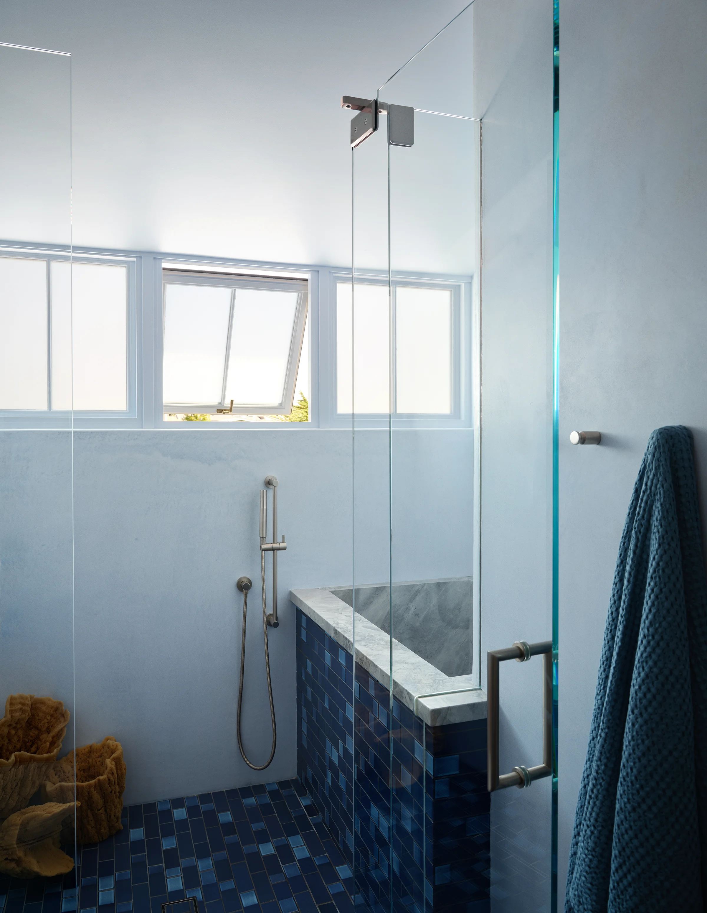 Primary shower with deep blue mosaic tile, marble bench, glass enclosure, and clerestory hopper windows flooding the space with natural light in Santa Cruz coastal home by Chroma.