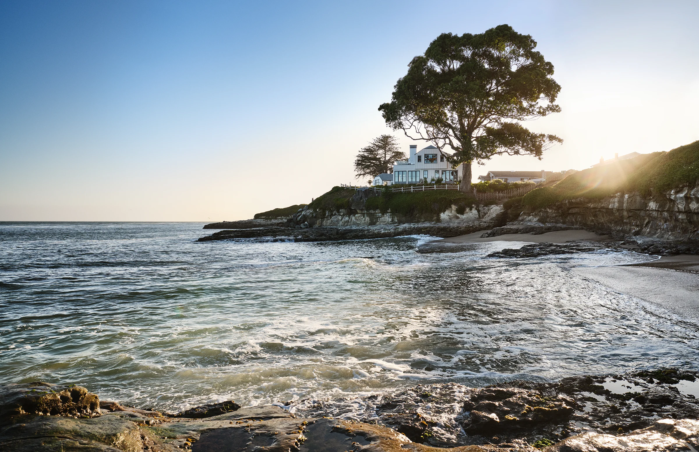 Santa Cruz cottage perched on rocky bluff at sunset, surrounded by Pacific waters on three sides, renovated by Chroma interior design and architect Benjamin McGriff.