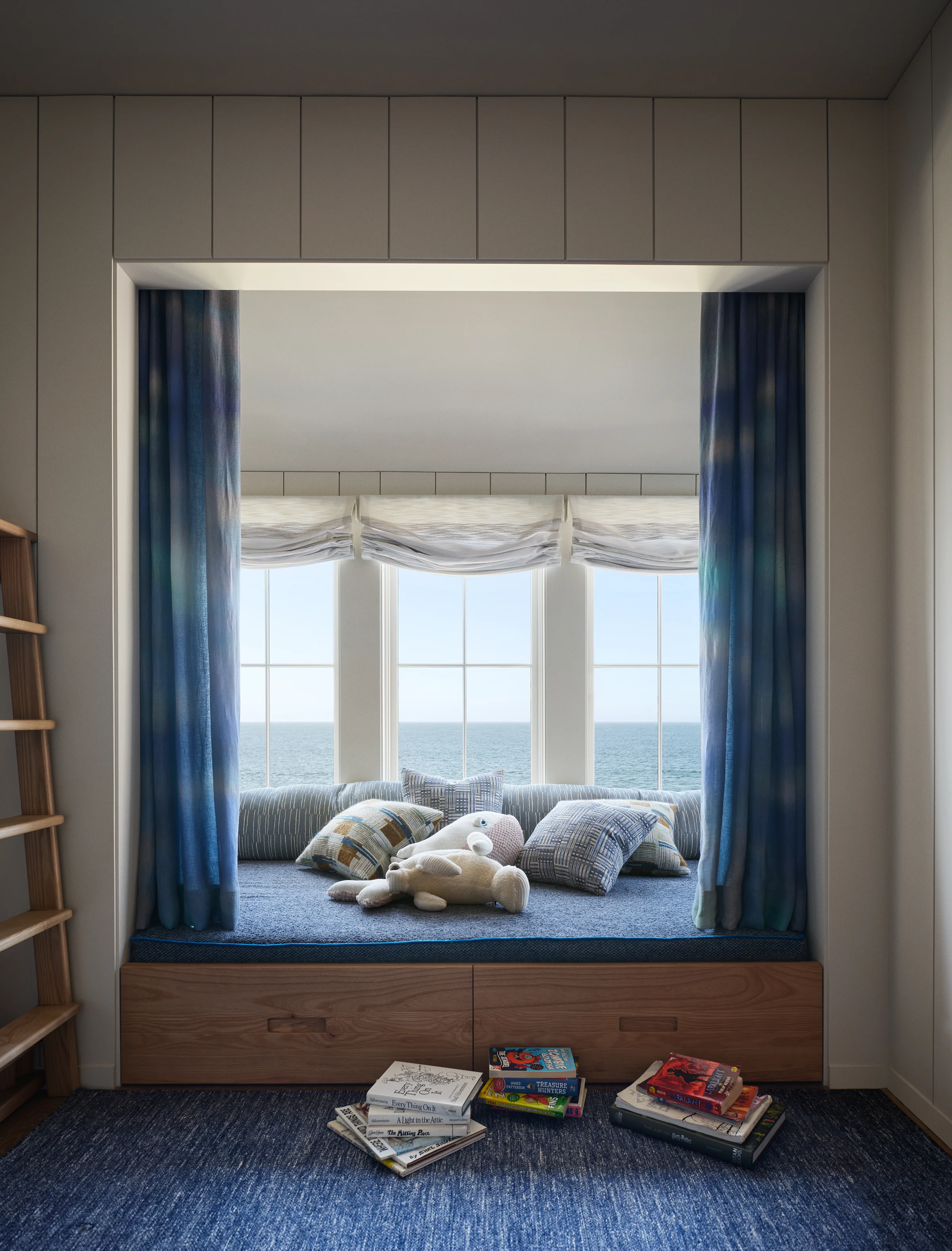 Children's bedroom with custom oak bunk beds, navy blue carpet, tie-dye-printed curtain alcove seat overlooking Monterey Bay in Santa Cruz cottage by Chroma.