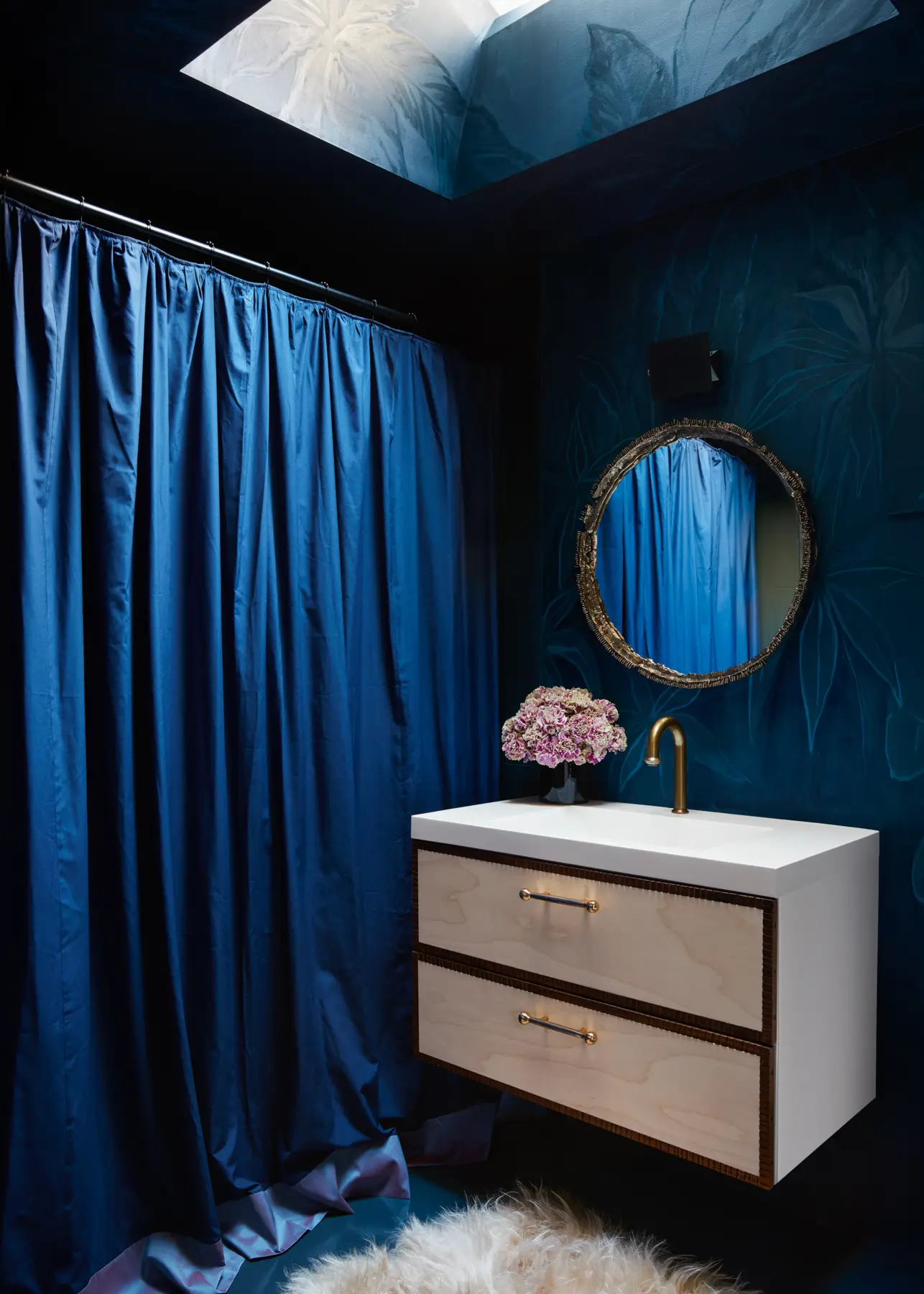 A sleek Dedar violette silk shower curtain lusters below a custom mural by Rafael Arana laced with vintage Charlotte Perriand sconces and cast brass mirror by Rafi Ajl and The Long Confidence.