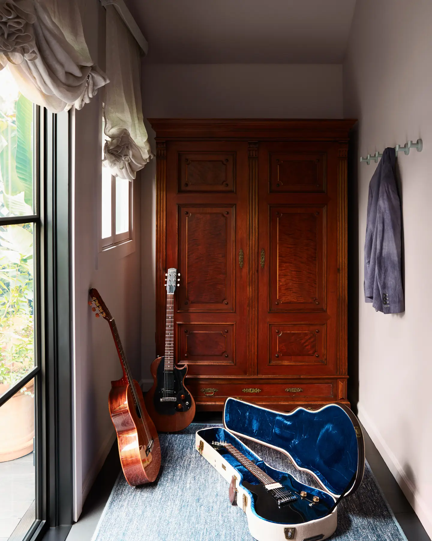 An antique wardrobe and custom 3HLinen Roman shades amp up sophisticated cool.