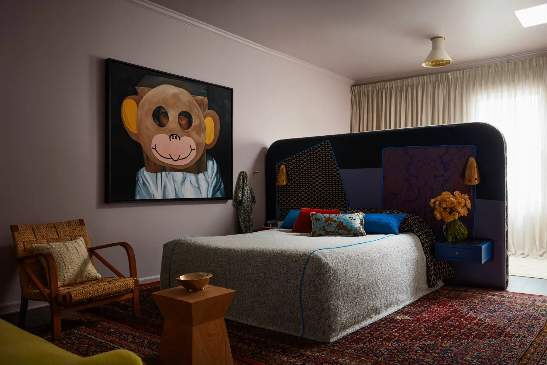 Cocooned with a pearl bouclé coverlet with Swiss velvet piping, a custom headboard in velvet, brocart lully, silk, and linen gestures with vintage David Marshall Brutalist sconces under the gaze of work by Kathryn Young.