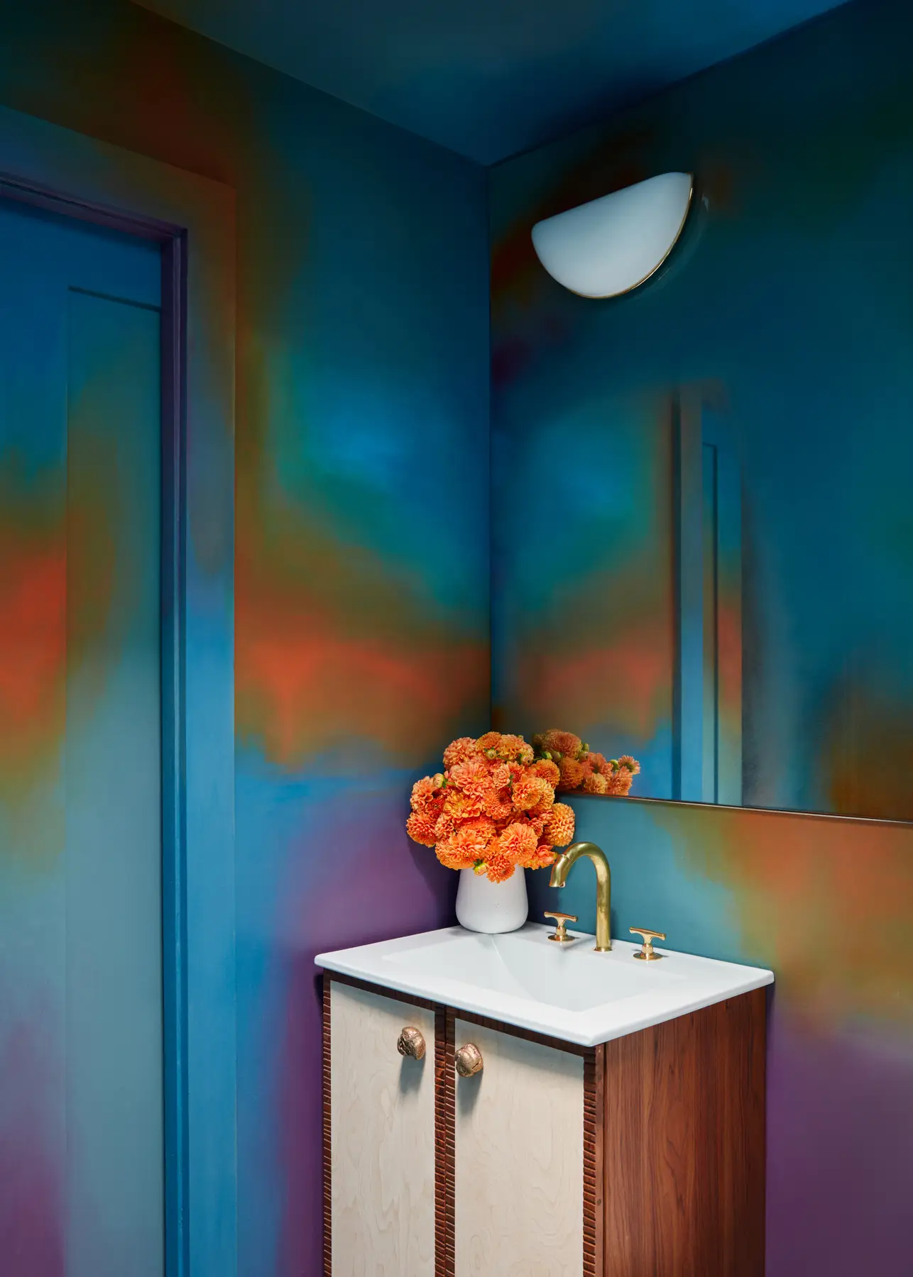 A cosmic Rafael Arana mural saturates the bath with a Jason Miller for Roll & Hill lamp, custom mirror by Victoria Weiss, and fixtures by Van Cronenburg.